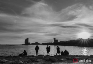 Silueta d'un grup de persones que contemplen la posta de sol a la Barceloneta